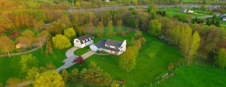 Aerial photo of white house on a large plot of land.