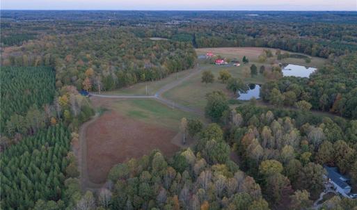 Aerial shot of open pasture land, 3 stocked pond, private driveway, wooded areas, and guest house seclusion from the main farm house.