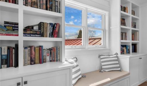 Second floor hallway w/ built in bookcases/display shelves w/ cabinet storage and day bench