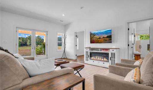Living room w/ built in electric fireplace cabinet, LVP flooring throughout, and cathedral ceilings