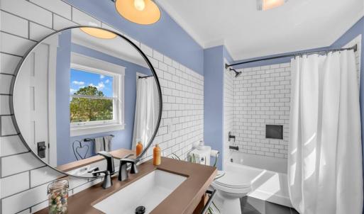 Second floor full bathroom with concrete countertop, backsplash accent wall, Pfister sink, black accent tile floor, and tub/shower combo w/ tile surround