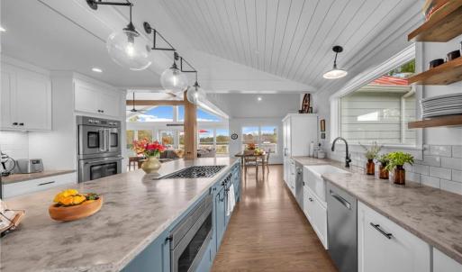 Honed quartz countertop, tile backsplash, farmhouse porcelain sink, & glass globe pendant light fixtures