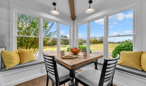 Breakfast nook w/ shiplap ceiling and exposed beam, built-in bench storage, and wall of windows for pasture views
