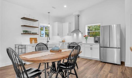 Guest house kitchen w/ Samsung appliances, 3 decorative floating shelves, and open floor plan to living room