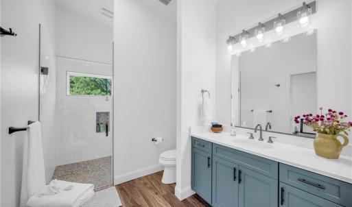 Full bathroom w/ frameless glass shower & tile surround, large vanity, and quartz countertop