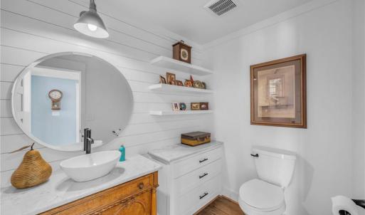 Main floor powder room w/ vessel sink and quartz countertop, 3 floating decorative shelves, and built in storage cabinet w/ quartz countertop