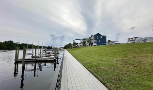 View of dock with a lawn and a water view