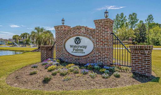 Community sign with a water view and a lawn