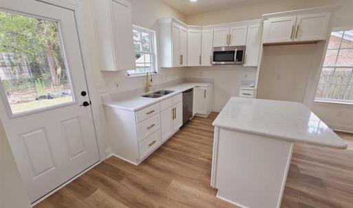 Kitchen with white cabinets, a center island, stai