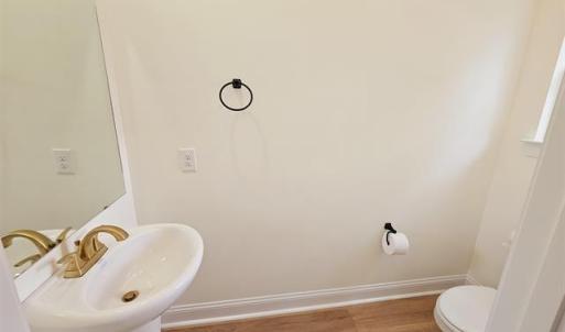 Bathroom featuring baseboards, a sink, toilet, and