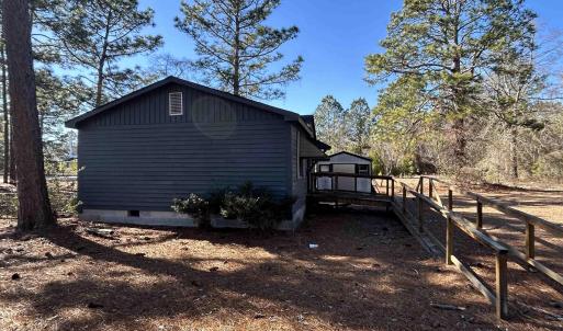 View of side of home with crawl space, fence, and
