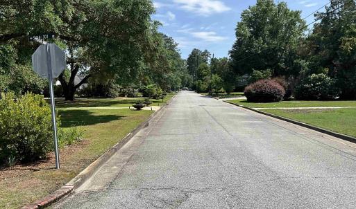 View of asphalt road with curbs, traffic signs, an