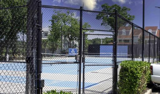 View of tennis court with a gate