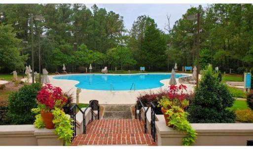 Community pool with a patio and view of wooded are
