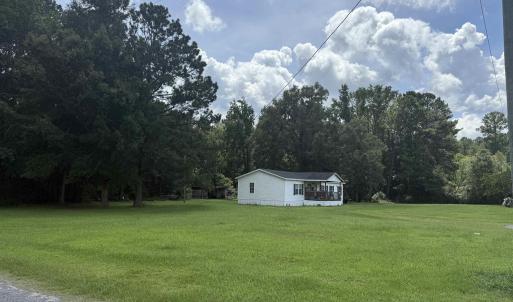 View of green lawn featuring a view of trees and a