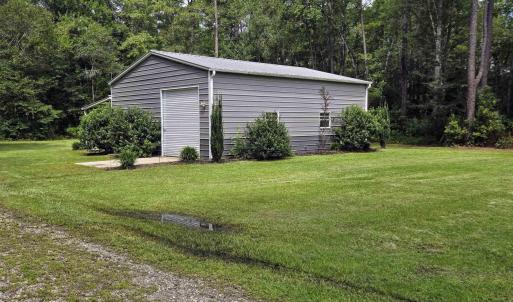 View of grassy yard with an outbuilding and a gara