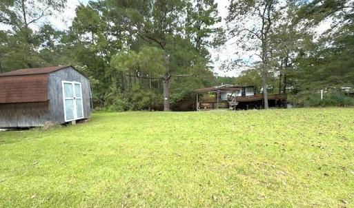View of grassy yard featuring a shed and a wooden