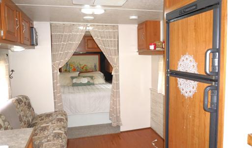 Bedroom with paneled fridge and wood finished floo