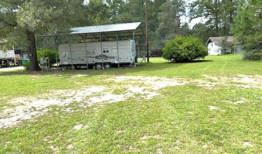 View of grassy yard featuring view of scattered tr