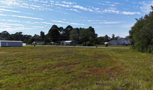 View of grassy yard with view of wooded area