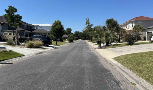 View of asphalt street with curbs and a residentia