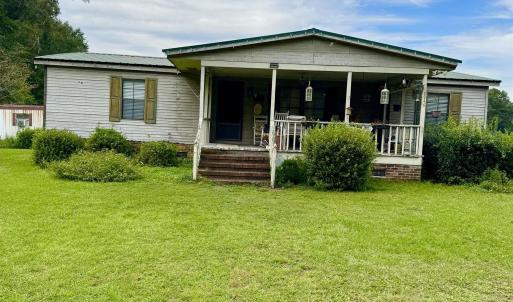 Back of house featuring covered porch and a yard