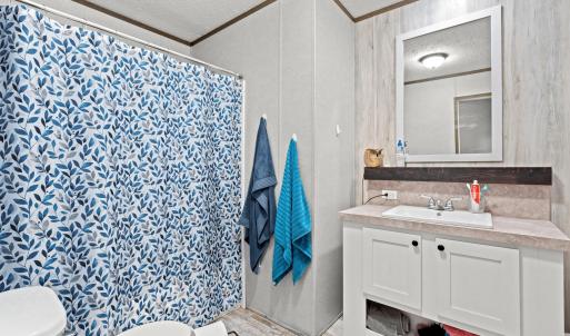 Full bathroom with a textured ceiling, vanity, lig