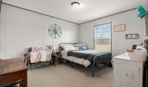 Bedroom with light colored carpet, a textured ceil
