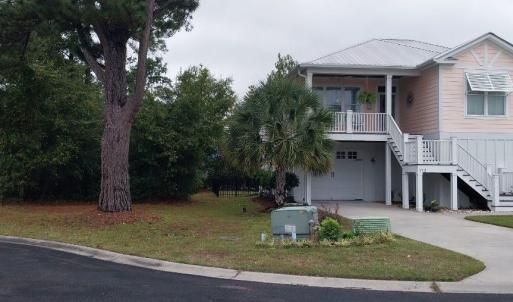 Raised beach house with stairs, driveway, and a ga