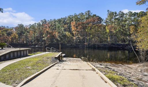 Dock with a boat ramp, a water view, and a forest