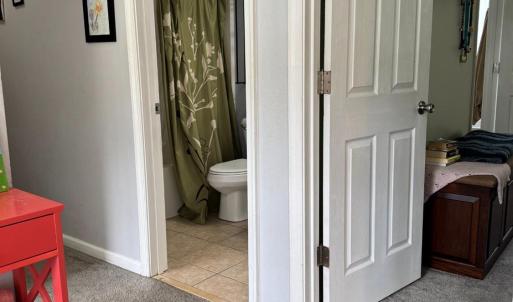 The Primary suite is the first door on the right. The hall bathroom for the other 3 bedrooms is shown here. Opposite the red table is the entrance to the 2nd bedroom.