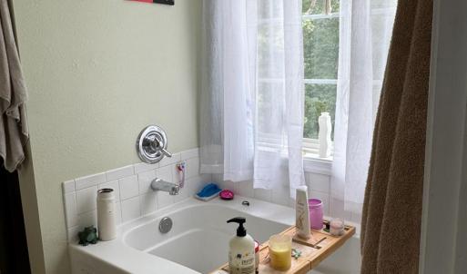 Add a tub with a window to relax enjoy a bath with a pretty view of trees.