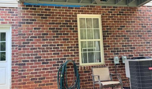 Outside this door is the upper deck. The bottom of the foundation is brick. The siding above it is vinyl. The seller created a patio here with terra cotta bricks. It is a great place to sit in the shade to still enjoy being outside on a hot summer day.