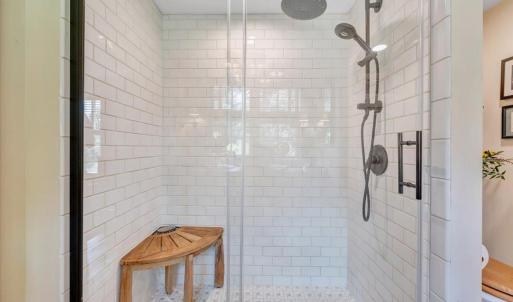 Walk-in shower with hand laid ceramic tile, rain shower head with hand shower attachment.