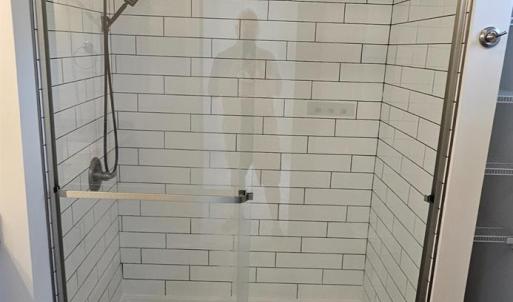 Primary bath shower floor to ceiling ceramic tile, glass door