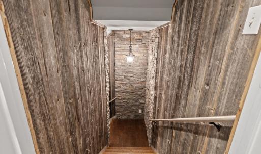 Stairs down to the basement area that has been made to replicate a wine cellar with wood and stone walls