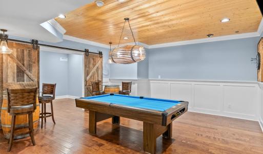 Pool table area and dart board looking into another game room or guest room