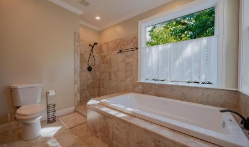 Primary bath with ceramic tile shower walls, jetted tub w/ ceramic tile surround , ceramic tile floors , double sink vanity, 2 built in linen cabinets