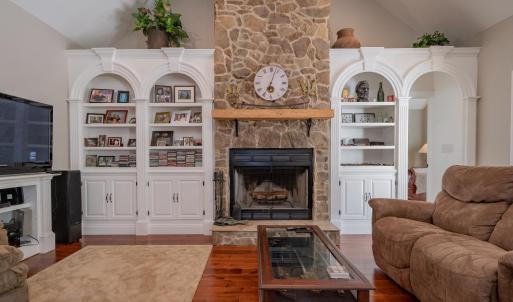 Great room w/ 14 ft ceiling, built in arched shelving & cabinets on both sides of rock FP, open to kitchen