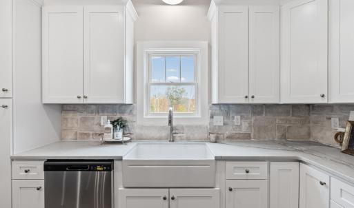 Kitchen has large island, stainless steel appliances, farmhouse sink, beautiful, upgraded lighting fixtures, quartz and stone backsplash