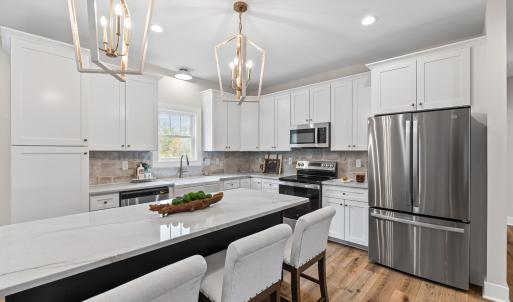 Kitchen has large island, stainless steel appliances, farmhouse sink, beautiful, upgraded lighting fixtures, quartz and stone backsplash