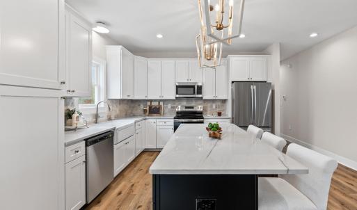 Kitchen has large island, stainless steel appliances, farmhouse sink, beautiful, upgraded lighting fixtures, quartz and stone backsplash