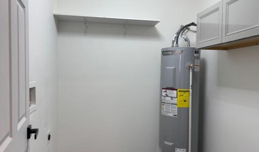 water heater, cupboard and panel box in the room with the washer and dryer. Right off the kitchen