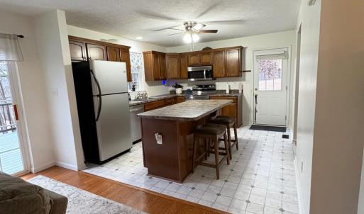Kitchen with new flooring and exit to side yard. Refrigerator, dishwasher, microwave and stove installed 11/25.