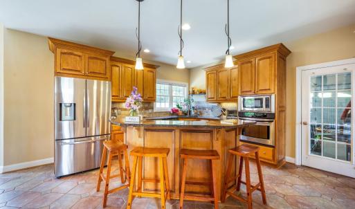 Kitchen with bar seating, custom cabinets, granite, induction cooktop, and tile! Easy access to the garage entry.