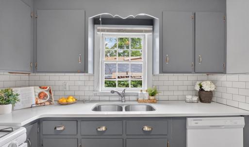 Updated kitchen with subway tile, backsplash, quartz counters, hardwood floors, and a walkout back porch. Window view over sink.