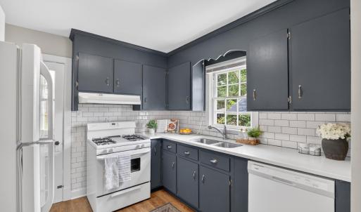 Updated kitchen with subway tile, backsplash, quartz counters, hardwood floors, and a walkout back porch. Window view over sink.
