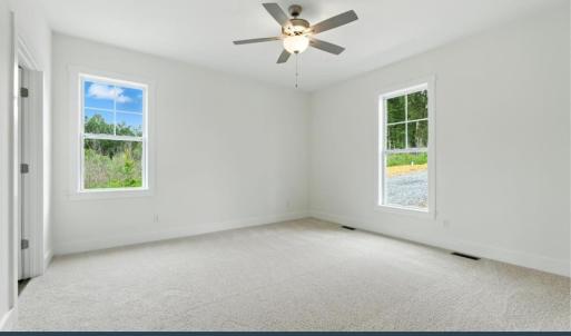 Spacious Primary Bedroom featuring carpet, two large windows, a ceiling fan