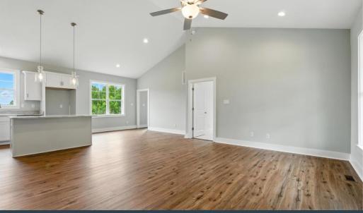 Open-concept interior featuring LVP flooring, cathedral ceilings, recessed lighting, and a ceiling fan