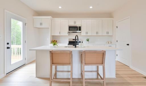 Open Concept kitchen with quartz counters, oversized island, door to deck, etc *Fridge ordered and scheduled to be installed.